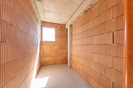 Empty Unfinished Interior Room in New Residential Building with Exposed Brick Walls and Concrete Ceiling, Real Estate Construction Site Ready for Renovation and Design Planning
