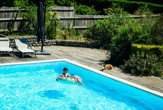 Beautiful young girl enjoying relaxing in the pool during a heatwave with her dog