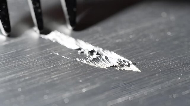 Closeup of a fork scraping a metallic surface with residue.
