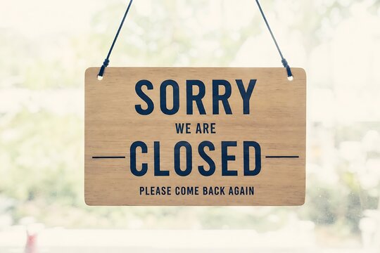 Wooden sign reading 'sorry we are closed please come back again' hangs by a string.