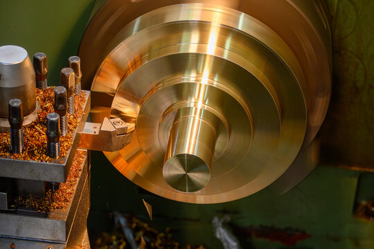 High-precision surface finish cut of a brass material part on a lathe turning machine in a blue-toned scene.