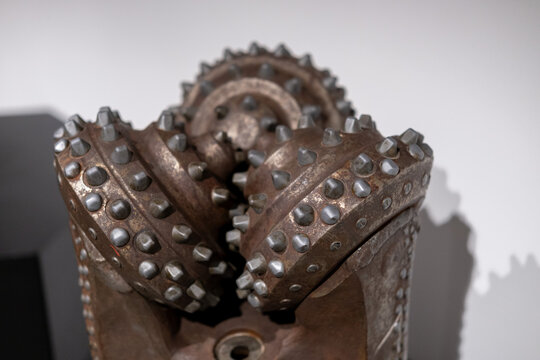 Close-up showing the interlocking steel teeth of an antique rusted tricone drill bit used for heavy geological boring.