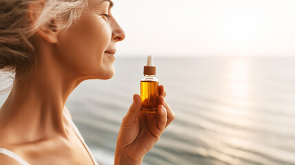 Fototapeta premium Mature woman enjoying natural skincare serum moment by tranquil ocean at golden hour sunset, celebrating aging gracefully