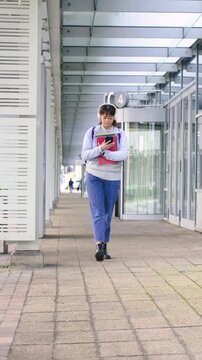 Vertical video: Walking commuter woman checking phone for directions while holding red binder at C4