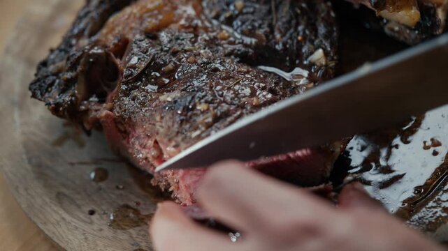 Close-up of hand slicing juicy, charred steak. Steam rises as knife cuts through tender meat. Rich brown sauce pools on rustic wooden board. Perfect for food advertising, restaurant menus