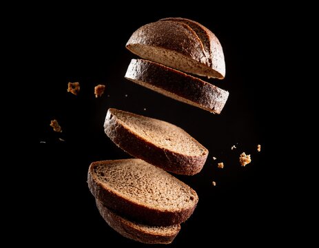 sliced dark bread pieces appear suspended in air against a stark black background