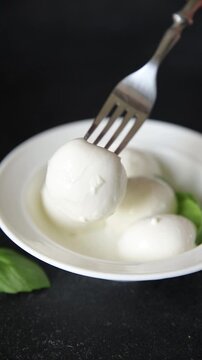Mini mozzarella or mini burrata soft, young cheese lunch or dinner tasty snack organic fresh and gourmet food background on the table rustic food top view copy space