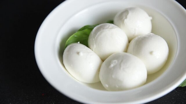 Mini mozzarella or mini burrata soft, young cheese lunch or dinner tasty snack organic fresh and gourmet food background on the table rustic food top view copy space