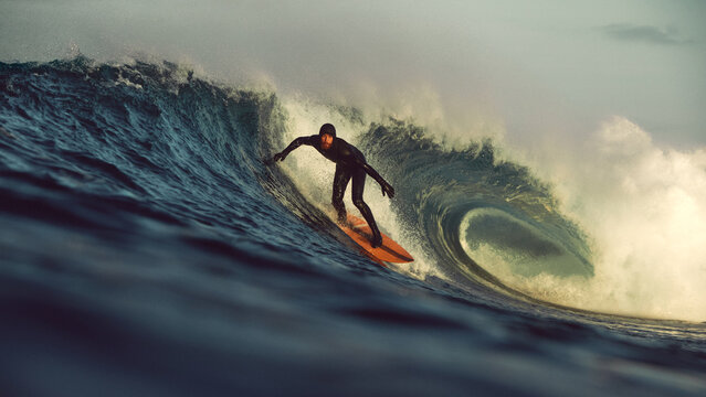 surfer taking off on big tubular wave at sunrise