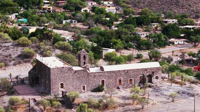 Aerial views of the church Mission of Santa Rosalia surrounded by mountains, desert, and a lush oasis in Mulege, Baja California Sur, Mexico.