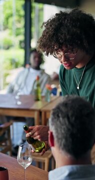 Man, wine tasting and waiter with bottle, restaurant and serving alcohol on valentines day and date. Happy, server and customer service for people in diner, couple and liquor recommendation at event