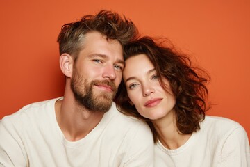 Obraz premium Portrait of a glad caucasian couple in their 30s wearing a simple cotton shirt isolated in pastel orange background