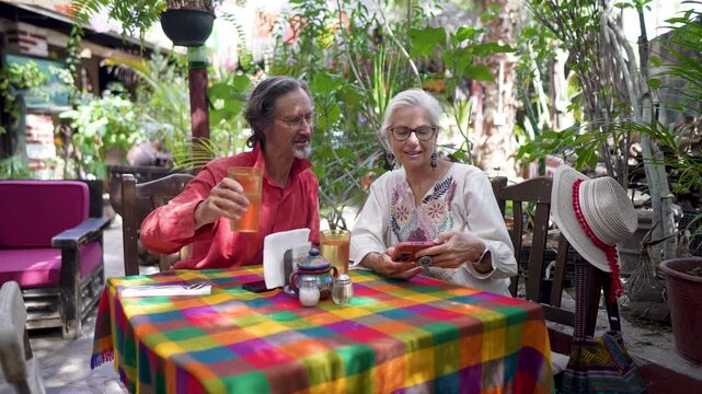 Mature woman enjoys local cuisine with a friend at a lively cafe, discovering Mulege in Baja California Sur, Mexico and its culture.
