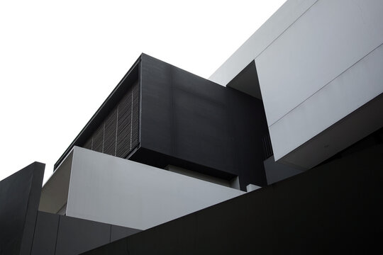 Low angle shot of modern minimalist architecture featuring striking black and white geometric building facade under a clear bright sky.