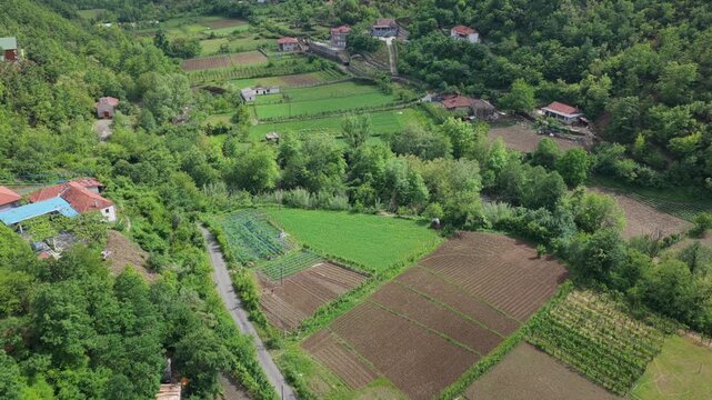 Aerial video of Katund i Vjeter village in the Mirdita Region, showcasing rustic homes and green agricultural fields.
