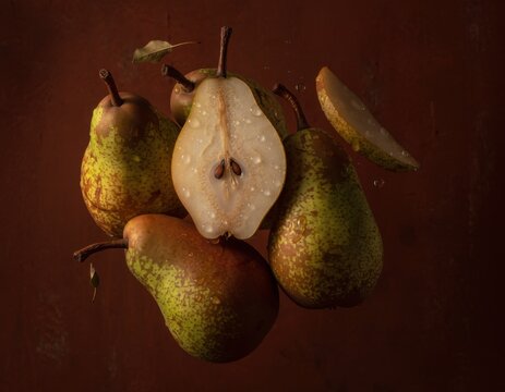 Floating juicy pears with fresh droplets on a dark red background showcasing fruit freshness and natural beauty