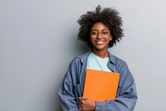 Young student smiling holding an orange folder in a relaxed pose for education website banner and lifestyle background