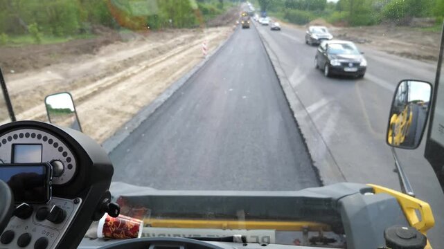 View on process of roadwork from inside cabin of steamroller. Roller laying new asphalt layer. Special machinery making road. Compactor constructing highway. Roadway repair by heavy machinery. Slow mo