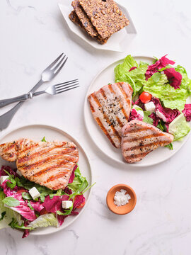 Delicious tuna served with salad and salt at a dining table