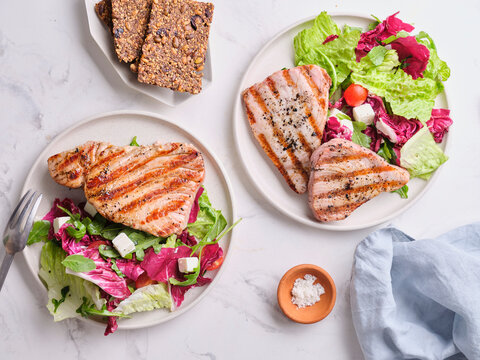 Grilled tuna served with salad and healthy sides on a clean table setting
