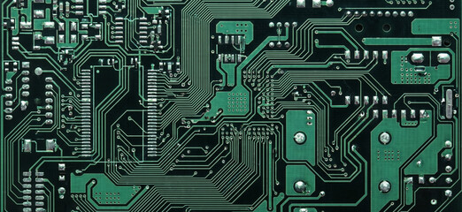 Fototapeta premium Close-up of a green circuit board with intricate pathways and components. Ideal for technology, electronics, or circuit design themes.