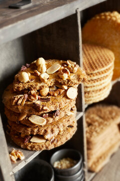 Assorted Dutch cookies including nut biscuits and stroopwafels in a rustic wooden shelf