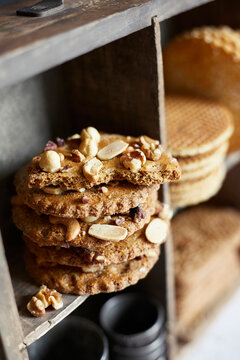 Assorted Dutch cookies including nut biscuits and stroopwafels in a rustic wooden shelf