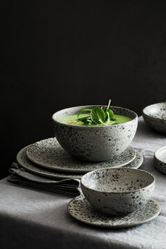 Green cream soup garnished with fresh microgreens served in a rustic ceramic bowl