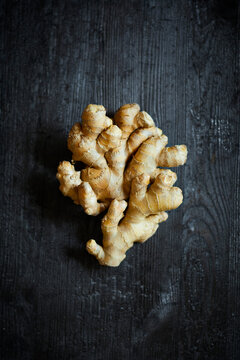 Fresh ginger root on dark wooden background, top view with dramatic lighting