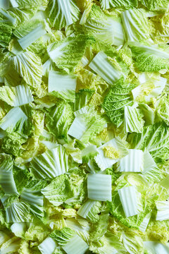 Top view of chopped Napa cabbage creating a fresh green vegetable background texture.