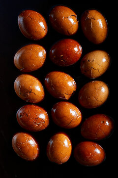 op view of Chinese tea eggs with cracked marbled shells on a black background.