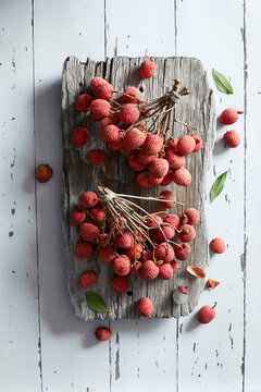 Fresh lychee fruit bunches on rustic wood, tropical harvest overhead
