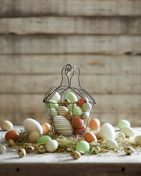 A rustic basket filled with farm-fresh chicken and quail eggs on straw, styled in a natural farmhouse setting.