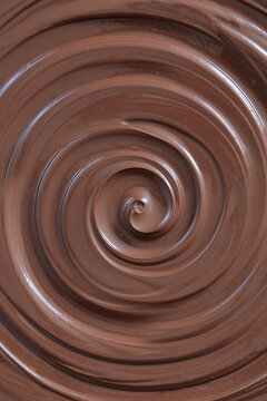 Close-up of glossy liquid milk chocolate swirling in a smooth spiral, showcasing a rich and creamy melted chocolate texture.