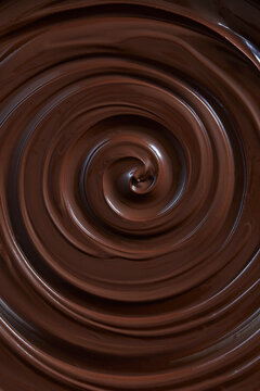 Smooth, glossy liquid dark chocolate swirling in a rich spiral, showcasing a luxurious melted chocolate texture in close-up.
