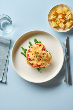 Italian chicken parmigiana (chicken parmesan) with roasted potato and green beans on a blue surface, from above