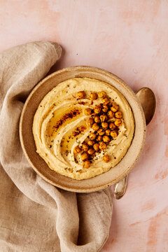 Hummus in Bowl with Spoon on Beige Background