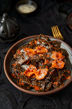 Black and orange pasta with parmesan on black table halloween season
