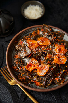 Black and orange pasta with parmesan on black table halloween season