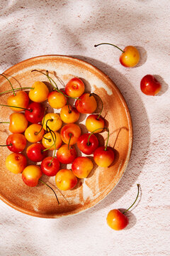 Cherries in a terracota plate with sunlight and shadow