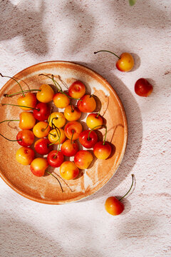 Cherries in a terracota plate with sunlight and shadow