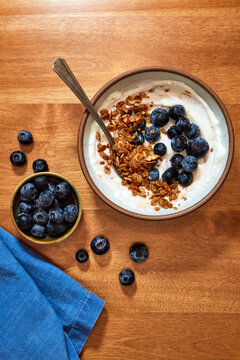 Simple Yogurt Bowl with Granola and Blueberries on a Wood Table