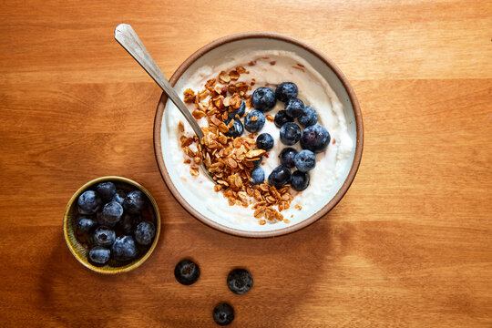 Simple Yogurt Bowl with Granola and Blueberries on a Wood Table