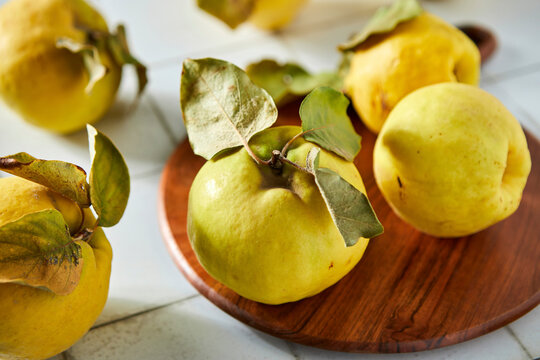 Quince Fruit on a Cutting Board and Tile Background