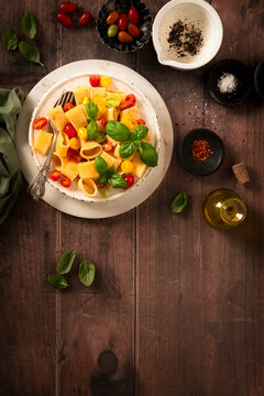 flat lay dish of macaroni with fresh raw tomatos and basil, sprinkled with black pepper, olive oil  and chilly.