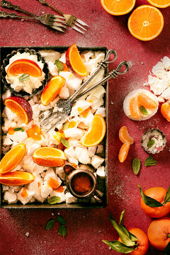 meringue and blood oranges mixed with whipped cream and marmelade as a topping, decorated with fresh mint leaves and sprinkled with icing sugar, top viev