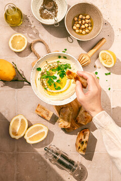 Hummus dip in a bowl, with lemons and parsley, high key