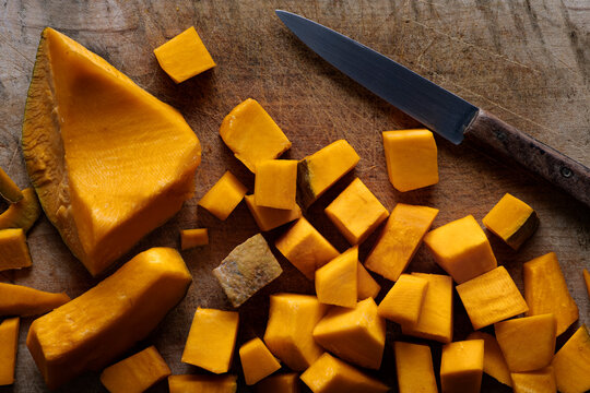 Pumpkin pieces on a wooden cutting board. Top view.