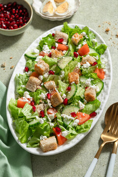 Lettuce salad in oval plate with eggs and pomegranate