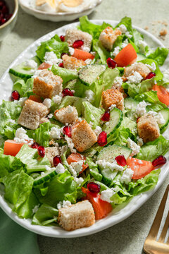 Closeup of serving plate with green salad, tomatoes, croutons and cucumber